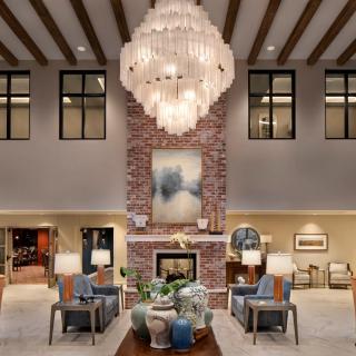 A modern, elegantly designed lobby featuring a large chandelier, comfortable seating area, and a central fireplace.