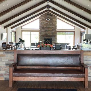 A cozy living room with a vaulted ceiling, featuring a central fireplace and a wooden bench in the foreground.