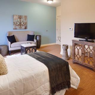 A cozy bedroom with a bed, couch, and television.