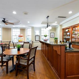 A modern and cozy dining area with wooden furniture and a bar counter, well-lit by natural light.