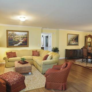 A cozy living room with a yellow sofa, patterned armchairs, and tasteful decor in a warm setting.