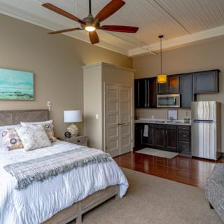 A cozy studio apartment featuring a comfortable bed, a kitchenette, and modern interior design elements.