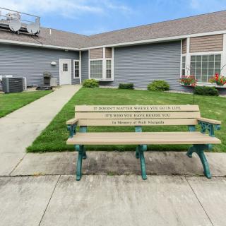 A wooden bench is placed in front of a modern building with well-maintained landscaping.