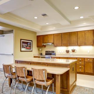 A modern kitchen interior featuring wooden cabinets and a central island with seating.