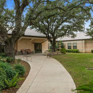 A welcoming house with a curved pathway and lush trees in the front yard.