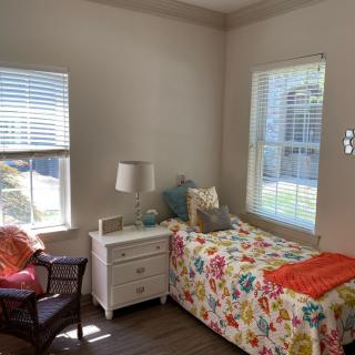 A cozy bedroom with floral bedding and natural sunlight streaming in.
