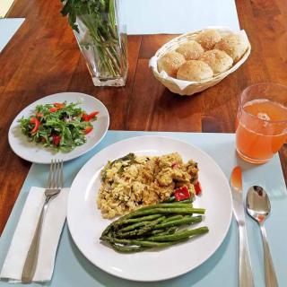 A delicious meal featuring pasta, asparagus, salad, and bread rolls served with a refreshing drink.
