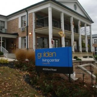 An office building with a sign in front of it, surrounded by landscaping.