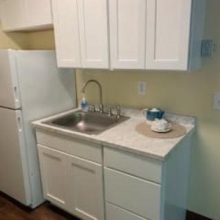 A compact kitchen with a white refrigerator, sink, and cabinetry.