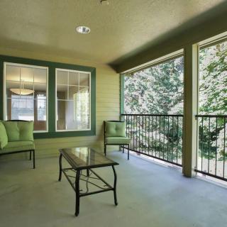 A spacious outdoor patio with comfortable seating and a view of surrounding greenery.