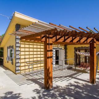 A yellow house with a wooden pergola on the patio.