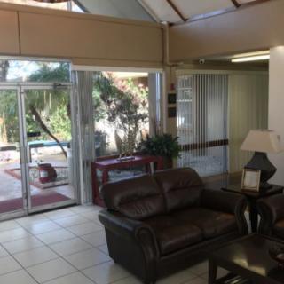 A cozy lobby area with a leather sofa and glass doors opening to an outdoor view.