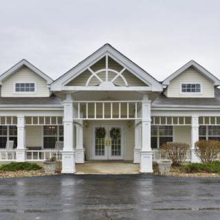 A front view of a large, white residential building with prominent columns and symmetrical design.