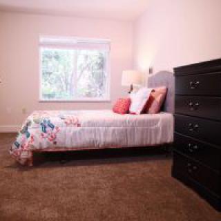 A cozy bedroom with a bed, dresser, and window.