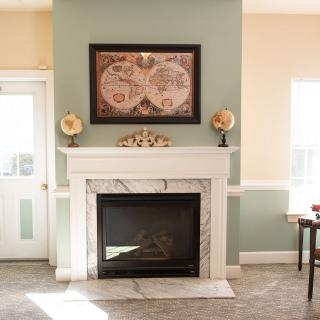 A cozy living room with a fireplace and map artwork above the mantel.