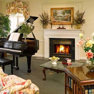 A cozy living room featuring a grand piano and a warm fireplace.