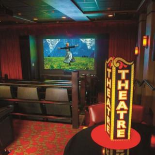 A cozy movie theater with red seating and a large screen displaying a film.