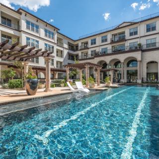 Luxurious apartment complex featuring a large outdoor swimming pool surrounded by elegant architecture.