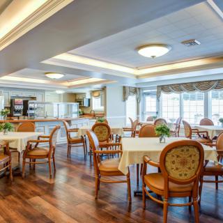 A spacious dining area with neatly arranged tables and chairs, featuring large windows and elegant lighting.