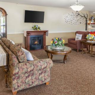 A cozy living room with a floral sofa, fireplace, and mounted television.