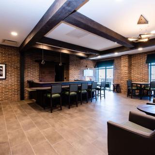 A modern bar interior with brick walls and wooden beams, featuring a seating area.
