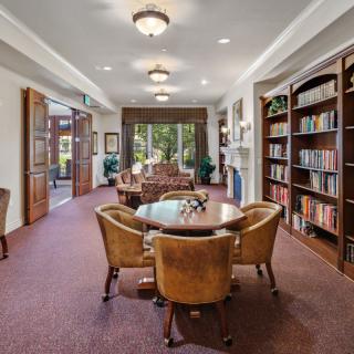 A cozy library room with bookshelves, comfortable seating, and elegant lighting.