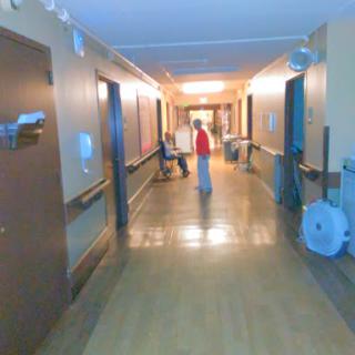 A view of a hospital hallway with two individuals observing the surroundings.