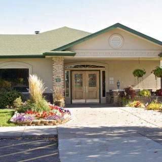 A welcoming building entrance with a green roof and well-maintained landscaping.