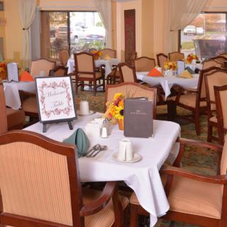 A cozy restaurant dining area with neatly arranged tables and chairs, featuring elegant table settings and floral decorations.