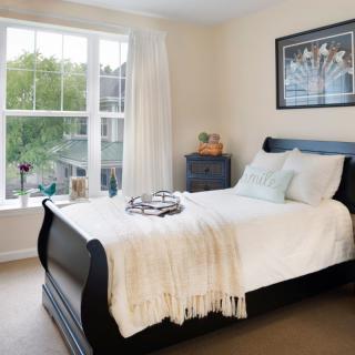A cozy bedroom with a large window and neatly made bed.
