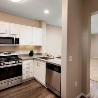 A modern kitchen with stainless steel appliances and wood flooring.