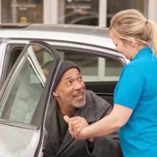 A person is being helped out of a car by another individual.