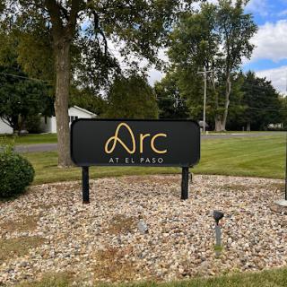 Sign for 'Arc' located in a grassy area.