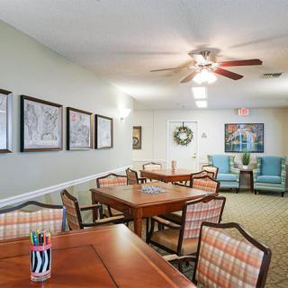 A cozy dining room with wooden tables and chairs, decorated with artwork and a ceiling fan overhead.