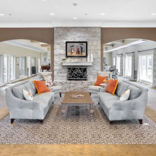 A modern living room with two matching sofas, a central coffee table, and a stylish fireplace adorned with artwork.
