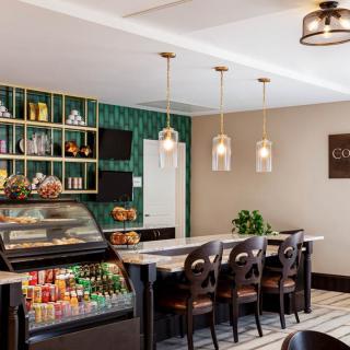 A modern cafe interior with stylish seating and lighting, featuring a counter and decorative shelves.