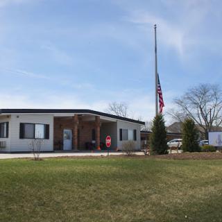 A view of a building with a flag at half-mast under a clear sky.