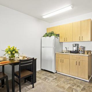 A small kitchen with a dining table, refrigerator, and cabinets.