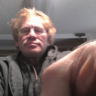 A casual portrait of a man with glasses and tousled hair, taken indoors.