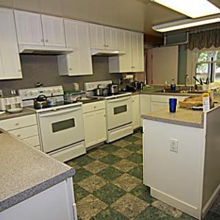 A spacious kitchen featuring multiple stoves and cabinetry with checkered flooring.