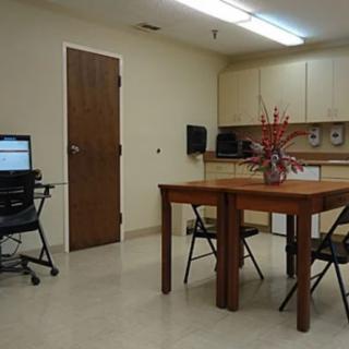 A small office meeting room with a table, chairs, and a computer setup.