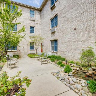 A serene courtyard with a garden and outdoor seating surrounded by a brick building.