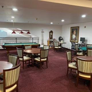 A cozy recreation room with multiple tables, chairs, and a pool table.
