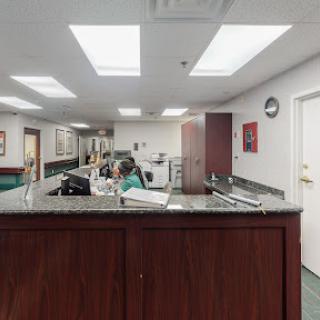 A view of a medical office reception area, featuring a front desk and staff members attending to tasks.
