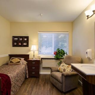 A cozy bedroom with a bed, armchair, and warm lighting.
