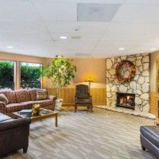 A cozy living room featuring comfortable sofas, a stone fireplace, and wooden paneling.