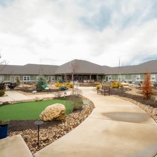 A wide view of a large building with a winding pathway and landscaped garden under a cloudy sky.