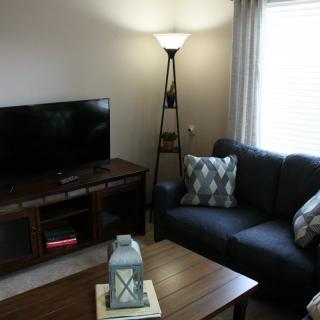A cozy living room with a sofa, a TV, and a standing lamp.