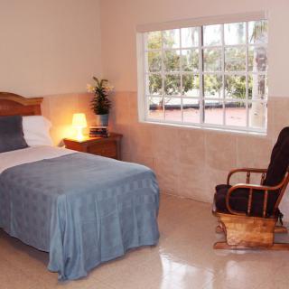 A cozy bedroom with a single bed, a rocking chair, and a large window.
