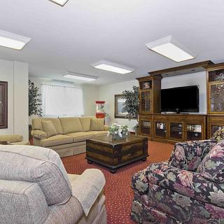 A cozy living room with a large entertainment center, featuring sofas and a television.